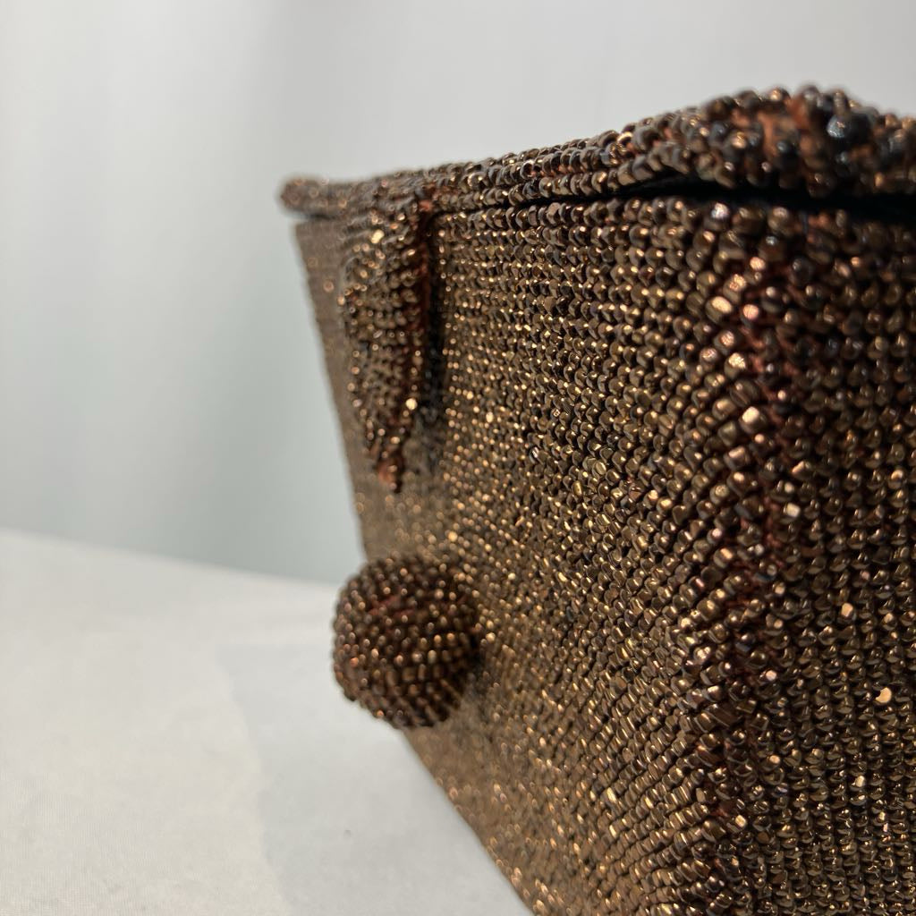 Close-up of a beaded clutch bag on a white surface with a light gray background