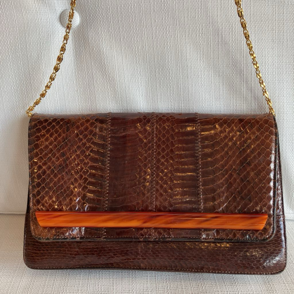 Brown snakeskin handbag with a gold chain strap on a light background