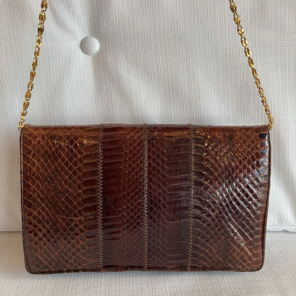 Brown textured handbag with a gold chain strap on a light background