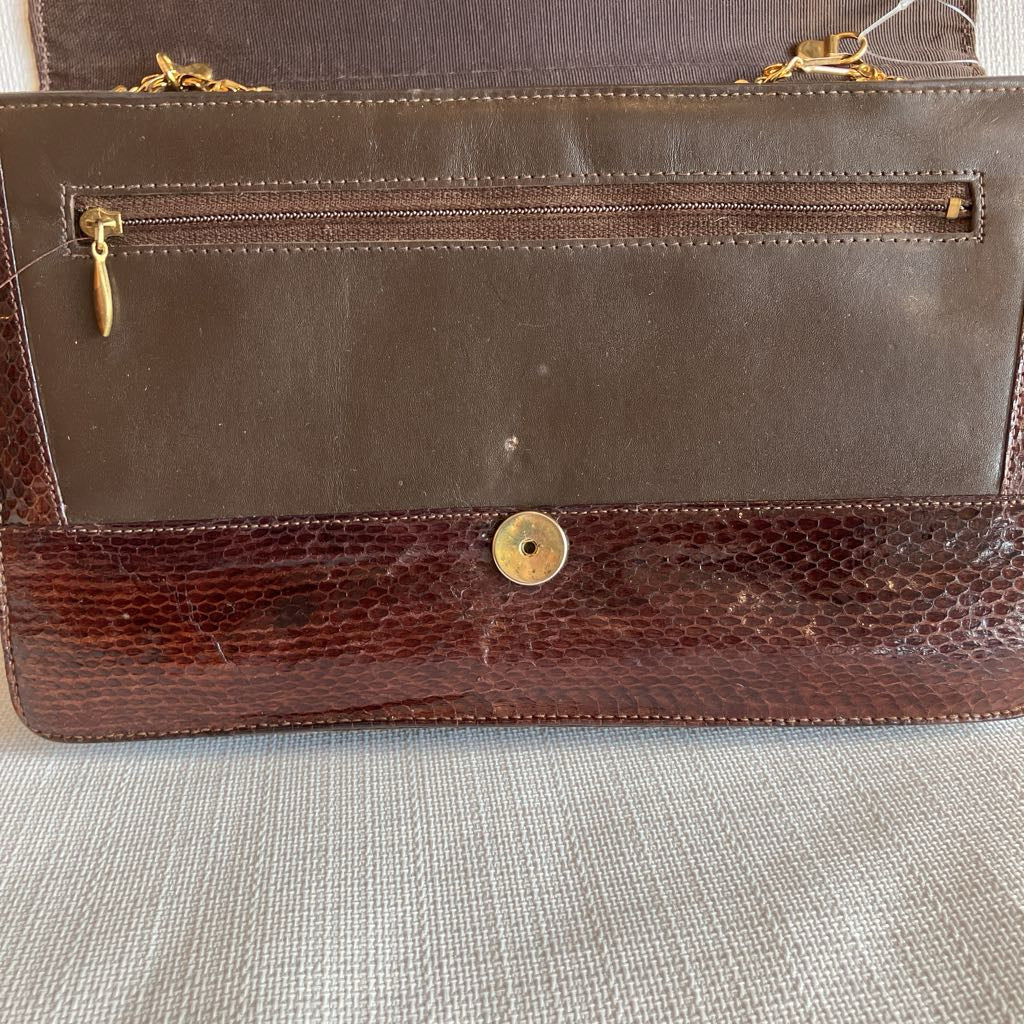 Brown leather handbag with gold accents on a textured surface