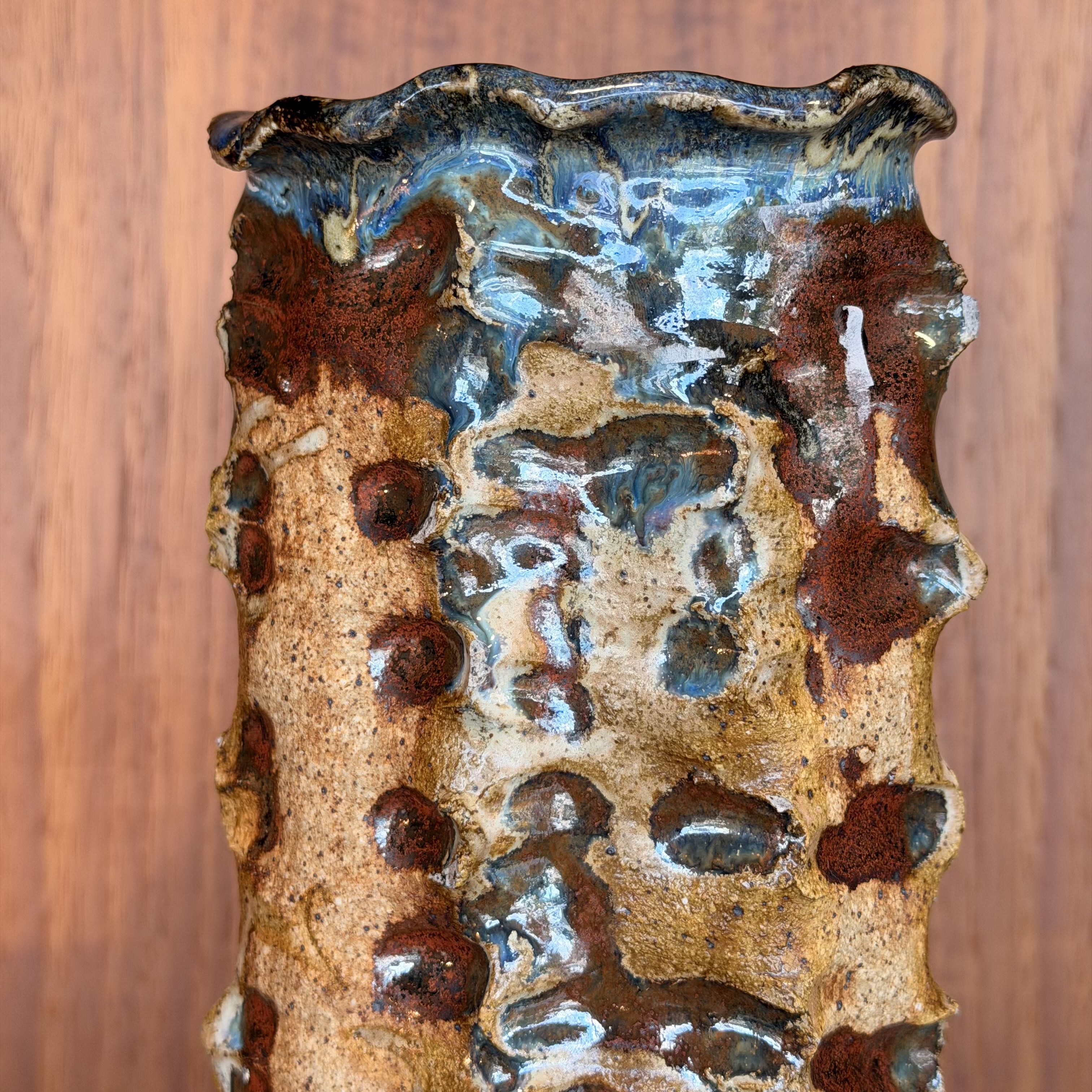 Decorative ceramic wall piece with brown and blue glaze on a wooden background