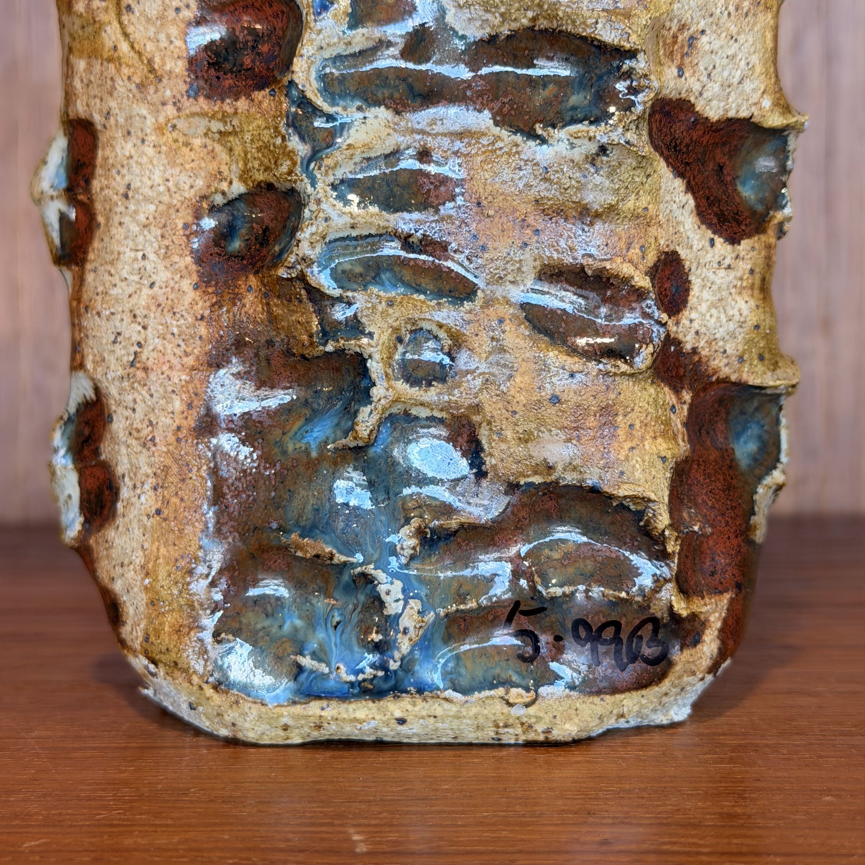 Textured ceramic piece with brown and blue glaze on a wooden surface