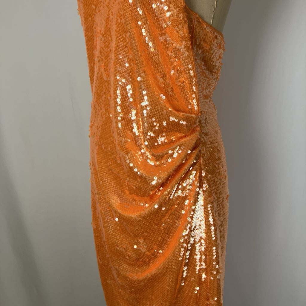 Orange sequined fabric on a mannequin against a gray background