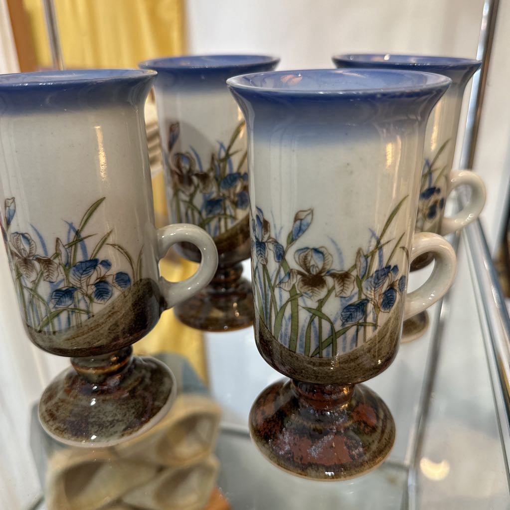 Set of ceramic cups with floral designs on a reflective surface