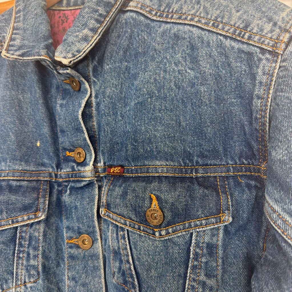 Close-up of a blue denim jacket with buttons and a brand label.