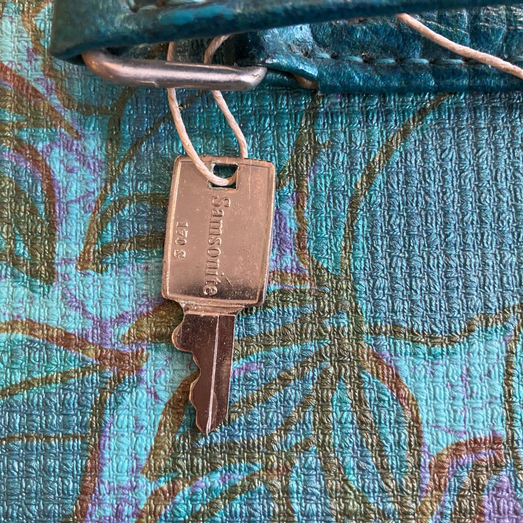 Bronze key attached to a textured blue fabric with floral patterns