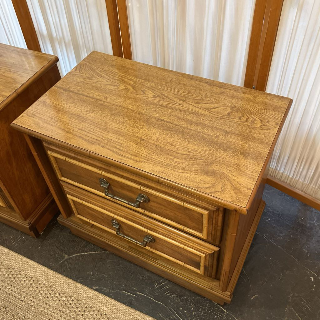 Wooden nightstand with two drawers on a dark floor.