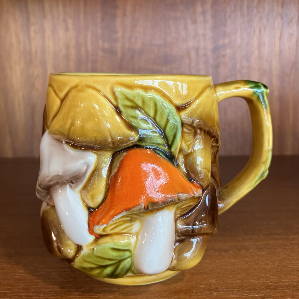 Decorative ceramic mug with mushroom design on a wooden surface