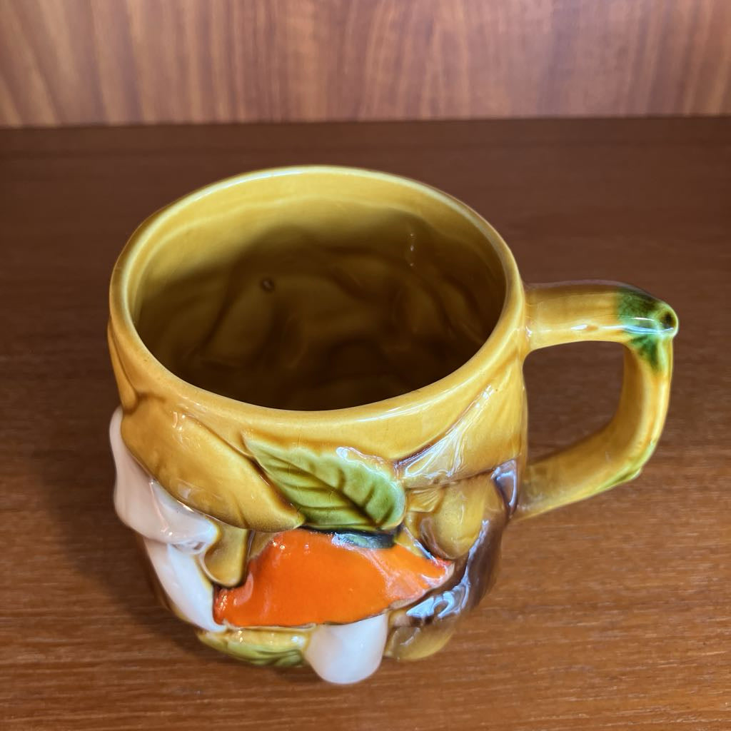 Decorative ceramic mug with a mushroom design on a wooden surface