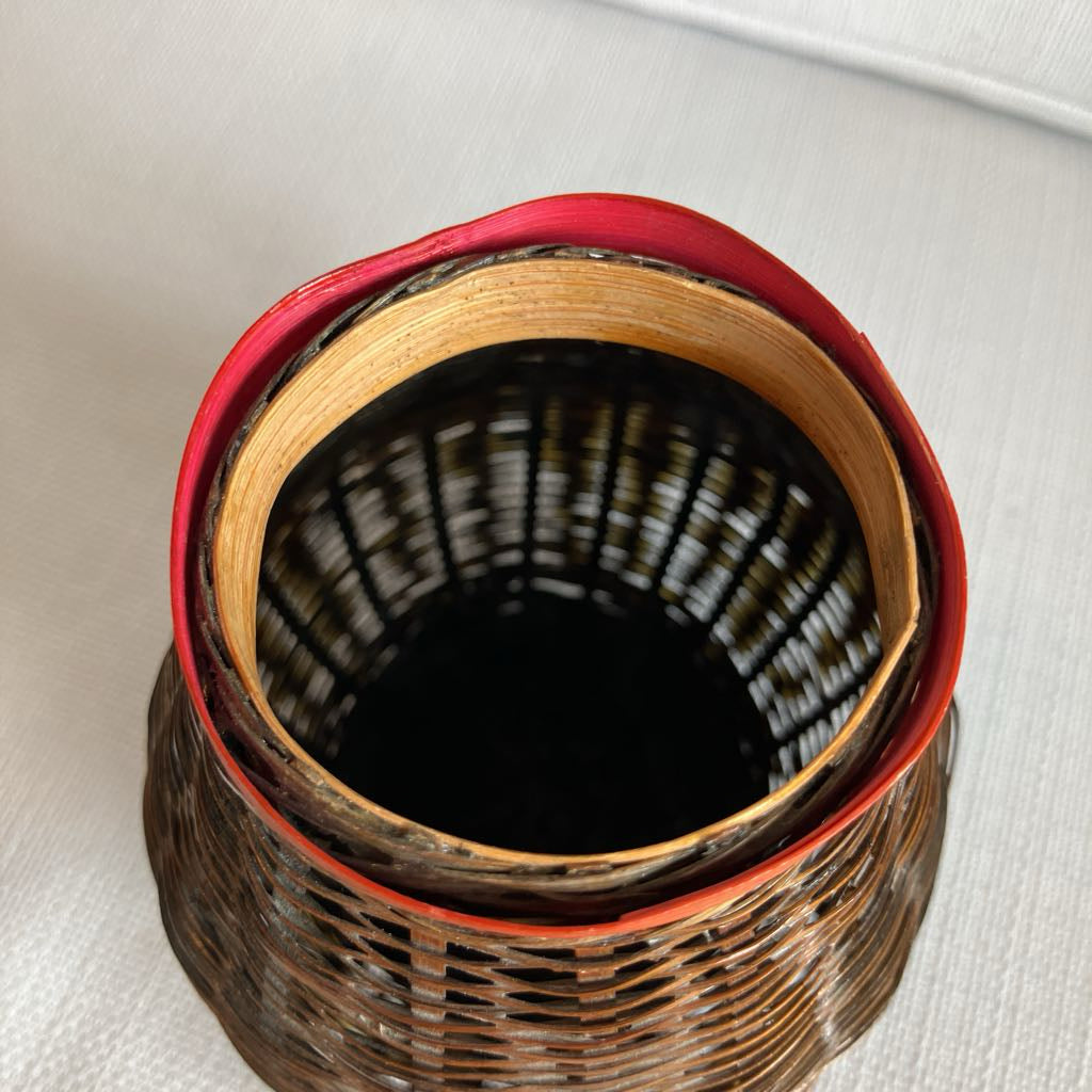 A wicker basket with a red rim on a white surface