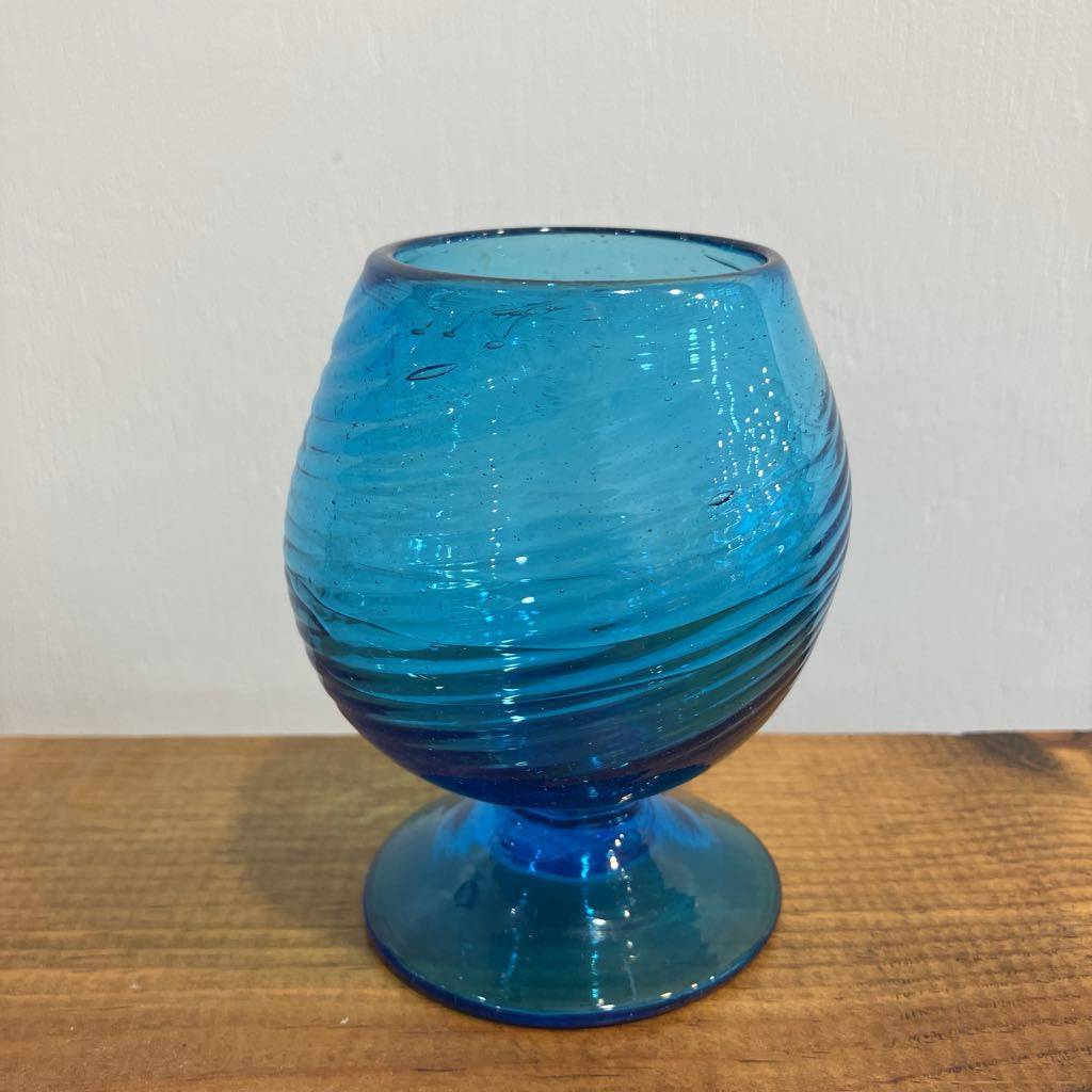 Blue glass goblet on a wooden surface with a white background