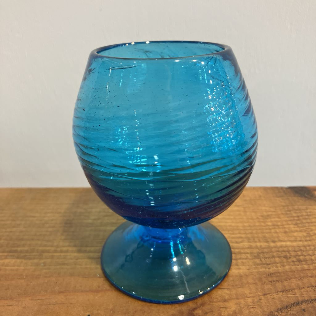 Blue glass goblet with ribbed design on a wooden surface
