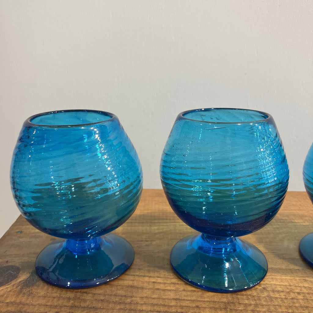 Two blue glass goblets on a wooden surface with a plain background