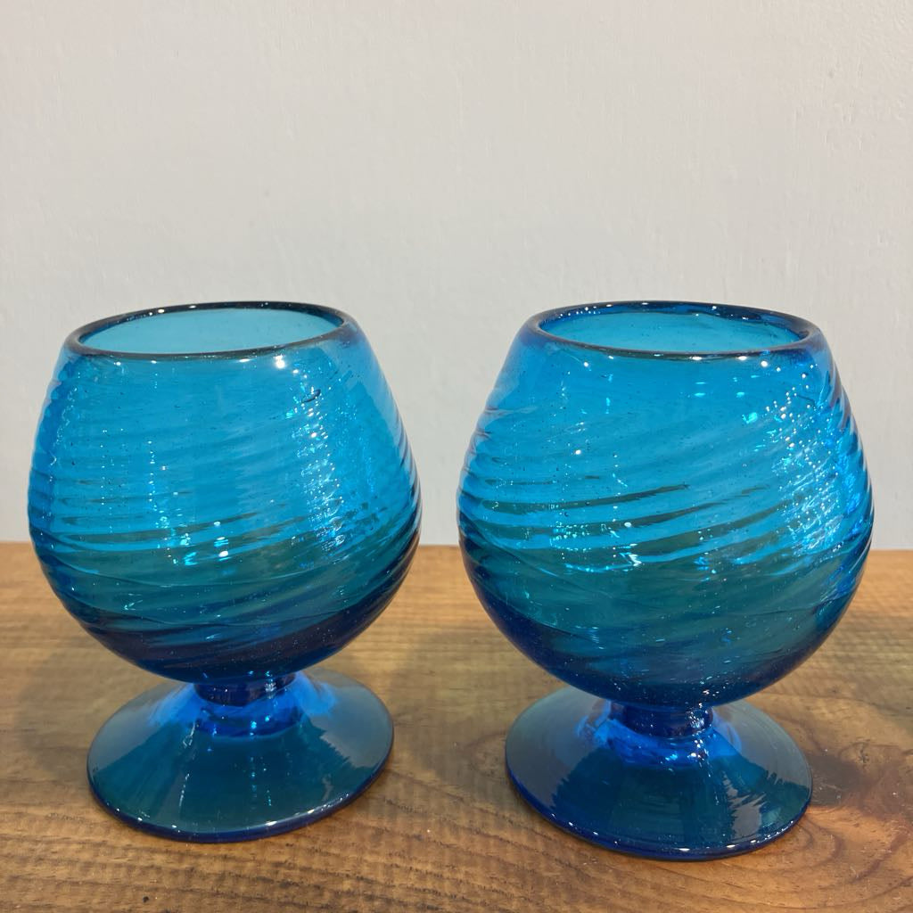Two blue glass goblets on a wooden surface with a white background