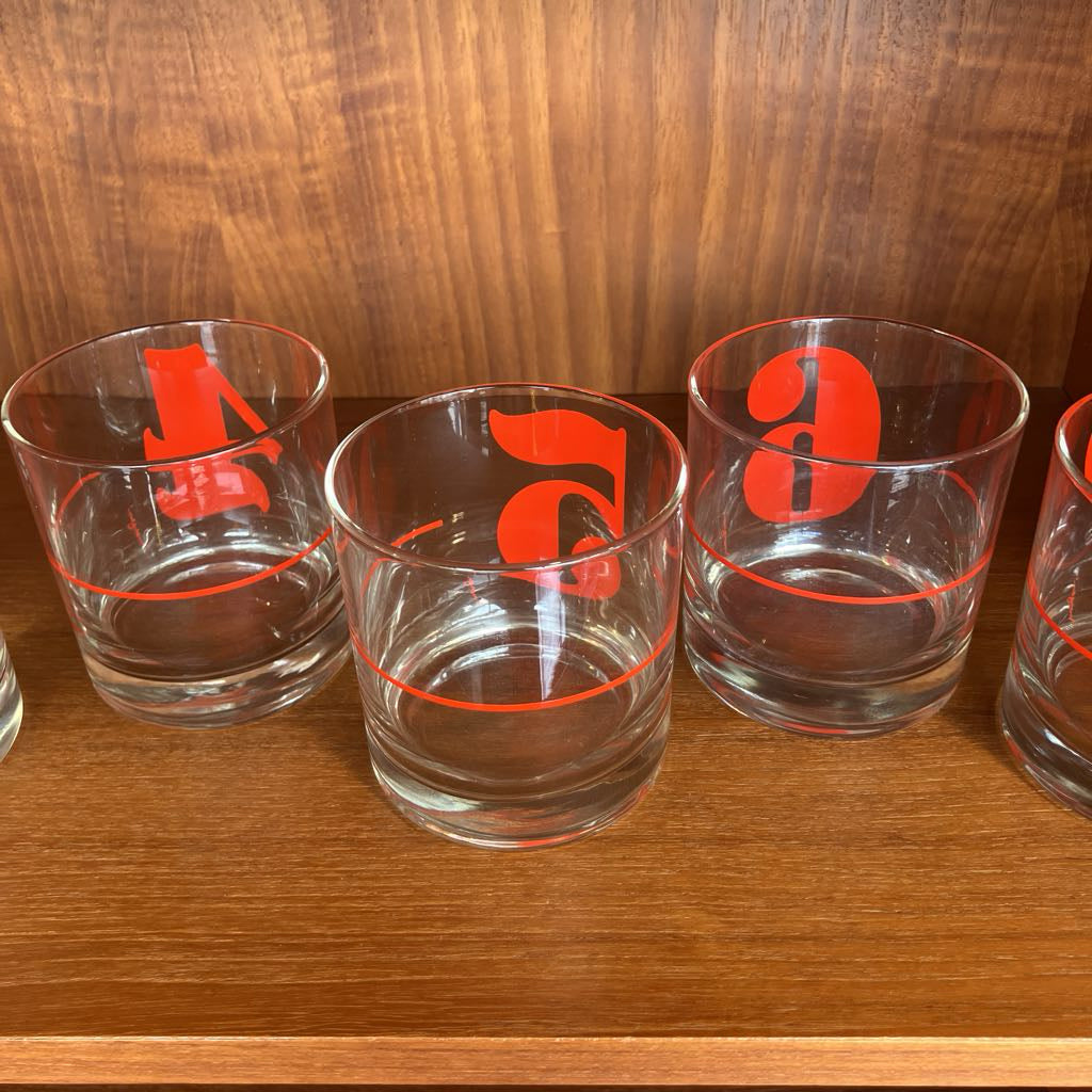 Clear glasses with red lettering on a wooden surface