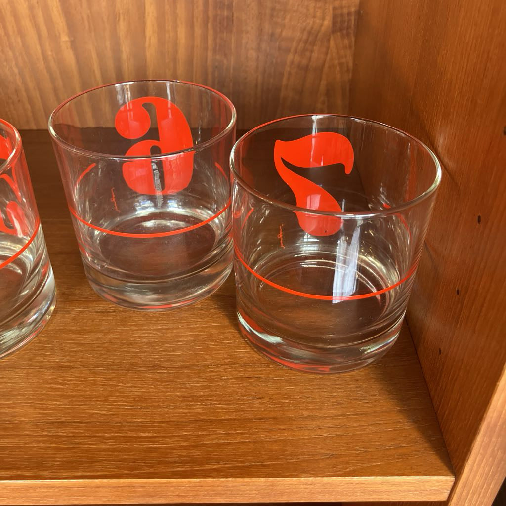 Three clear glasses with red and black designs on a wooden surface