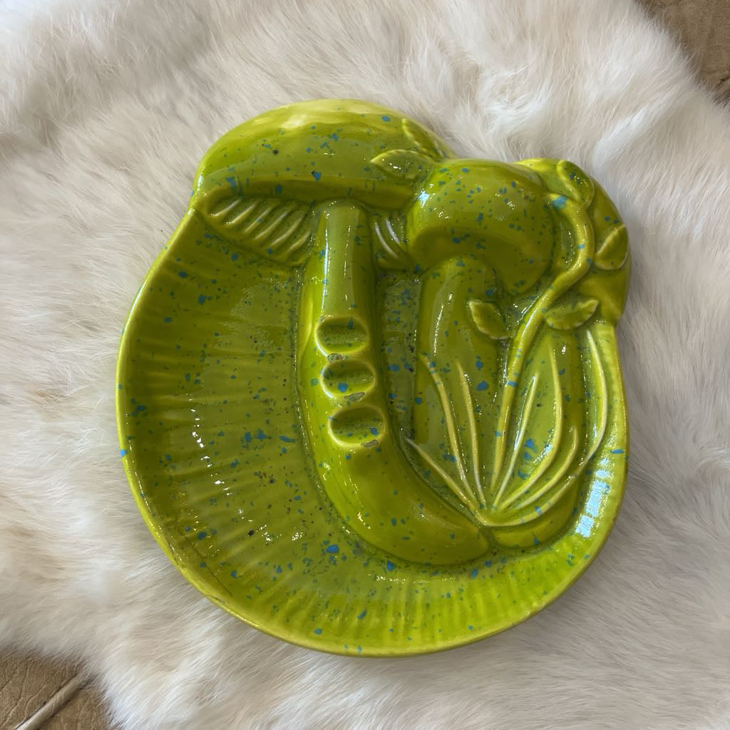 Green ceramic dish with a mushroom design on a fluffy white surface