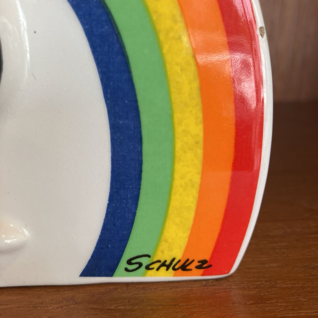 Close-up of a white object with rainbow stripes and 'Schulz' branding on a wooden surface.