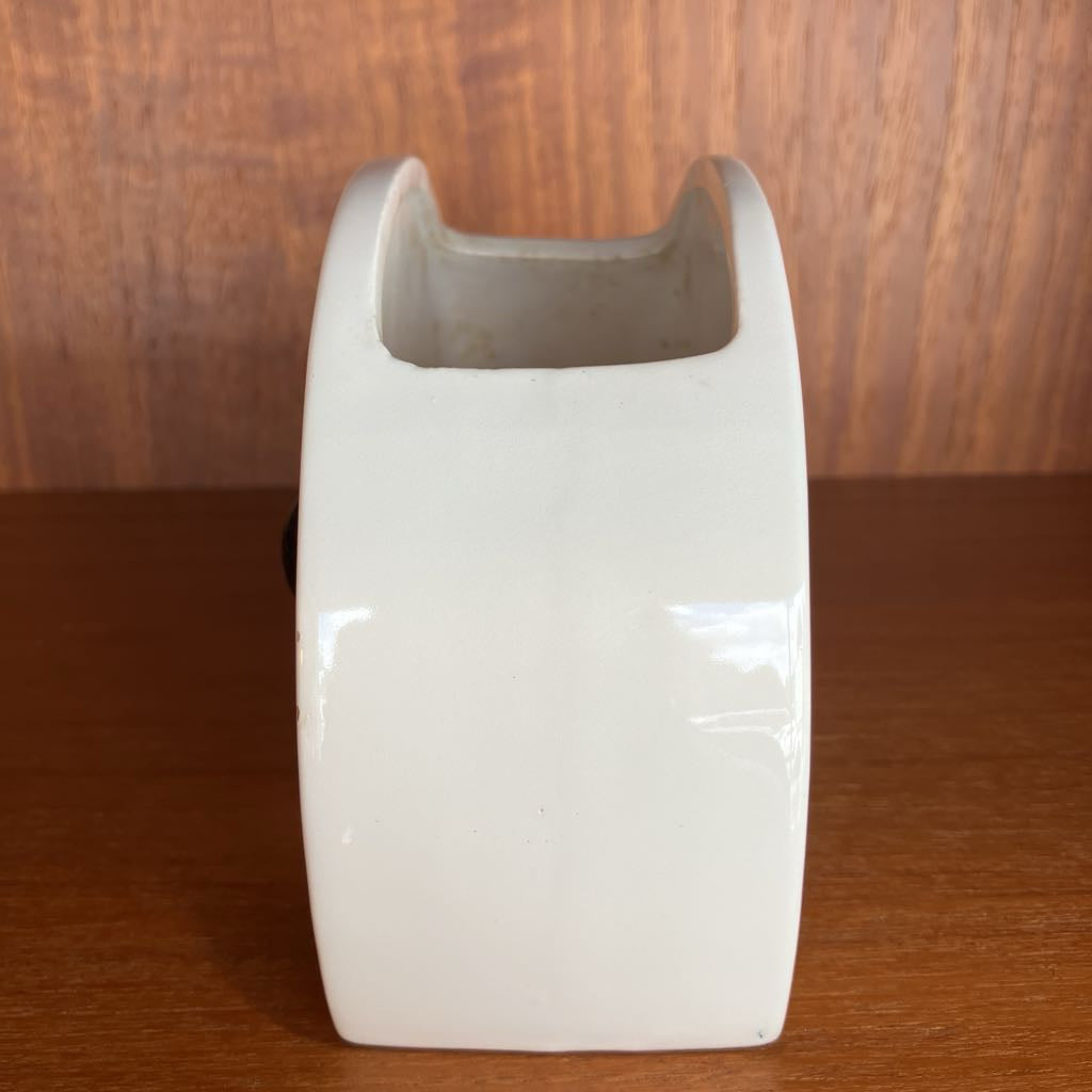 White ceramic vase with a brown interior on a wooden surface