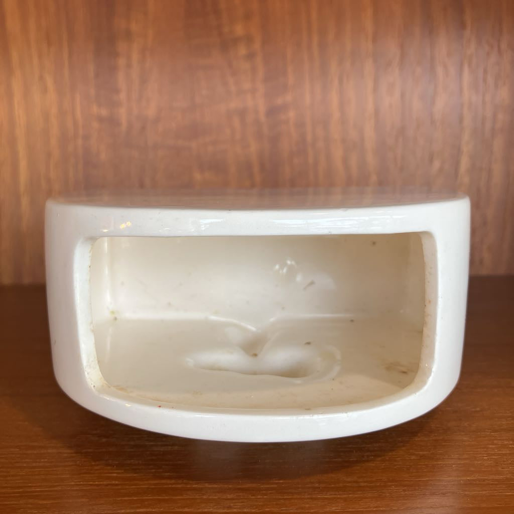 White ceramic planter with a textured surface on a wooden surface