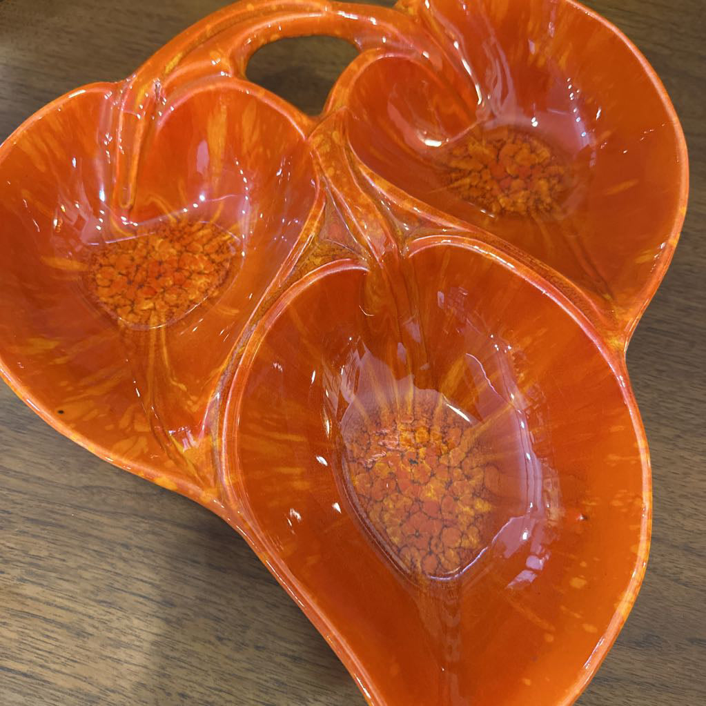 Orange ceramic dish with floral patterns on a wooden surface