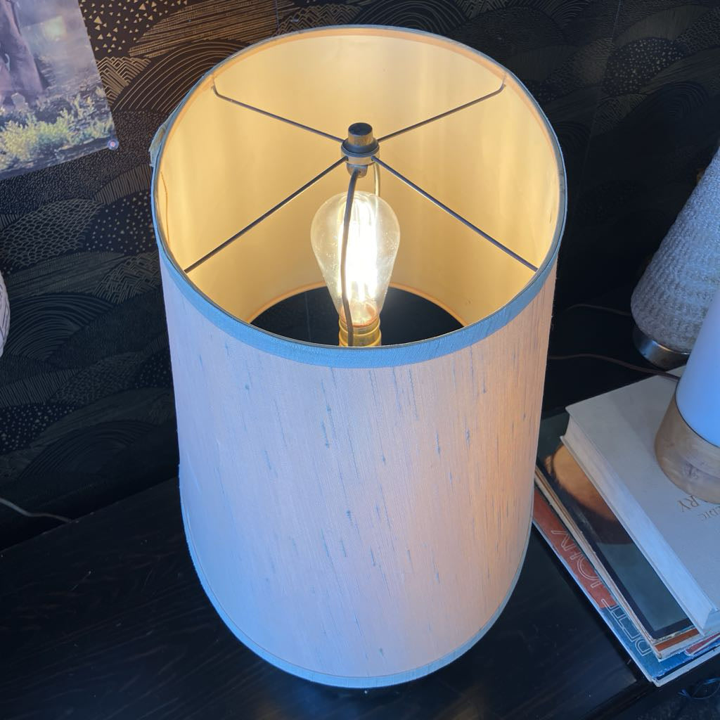 Table lamp with wooden base and beige shade on a dark surface