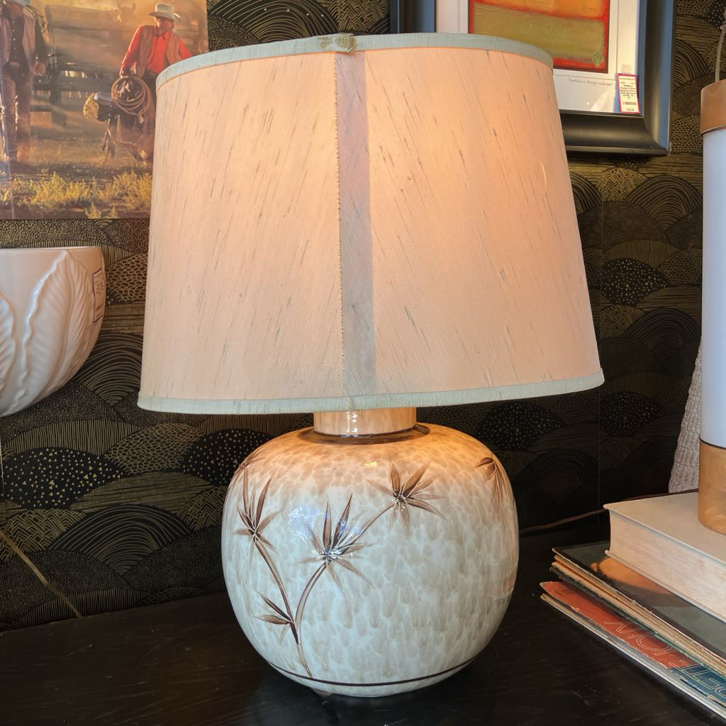 Decorative lamp with a textured base and beige shade on a table.