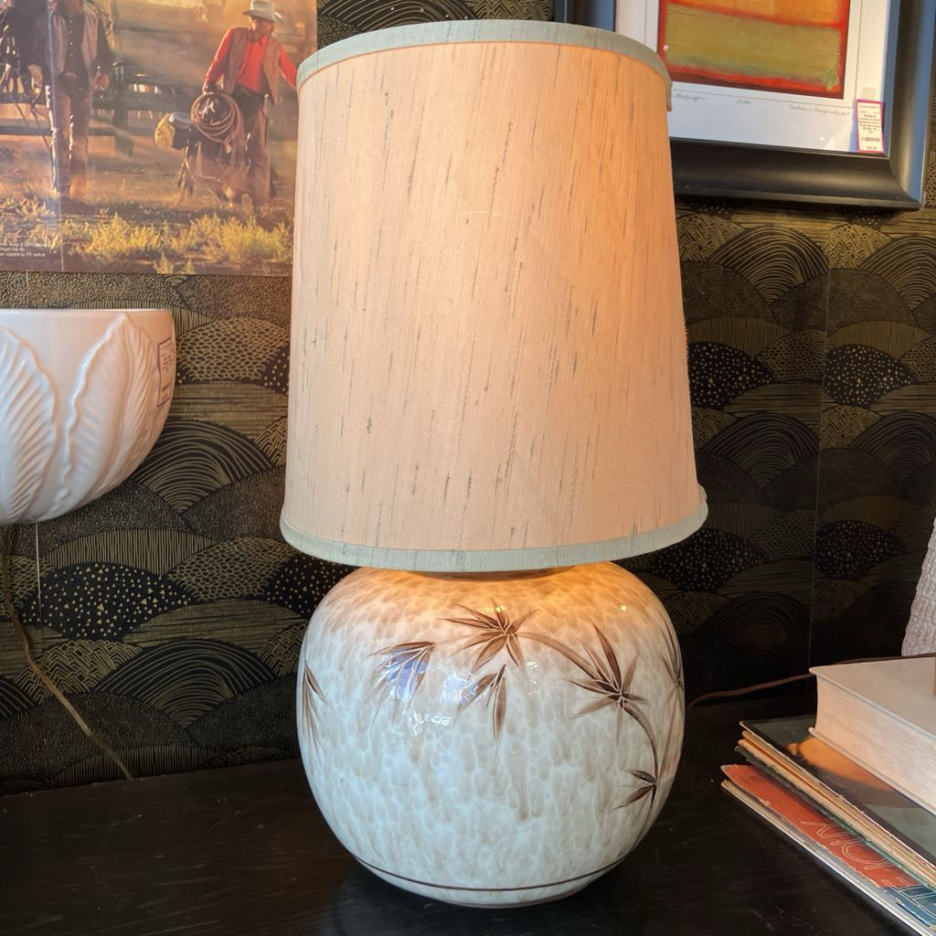 Decorative lamp with a textured base and beige shade on a table.