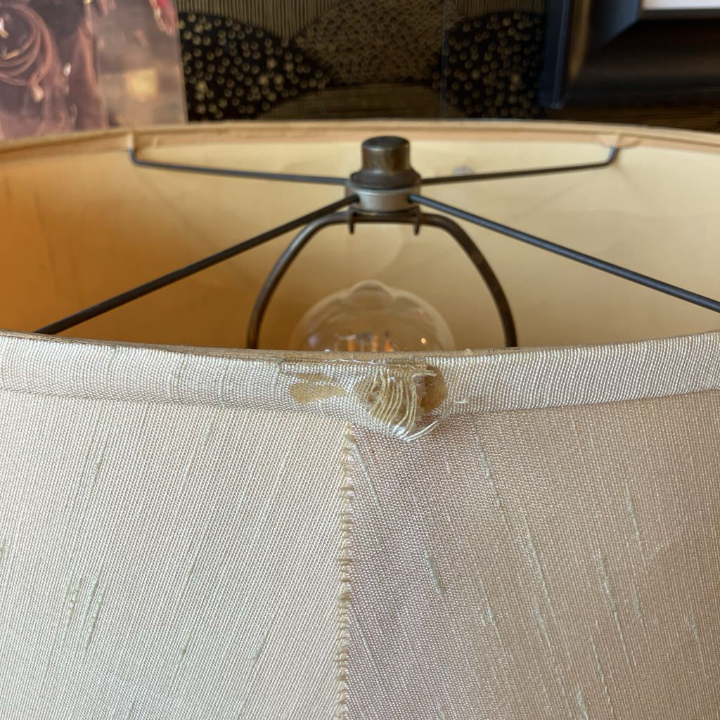 Close-up of a lamp with beige fabric shade and metal base.