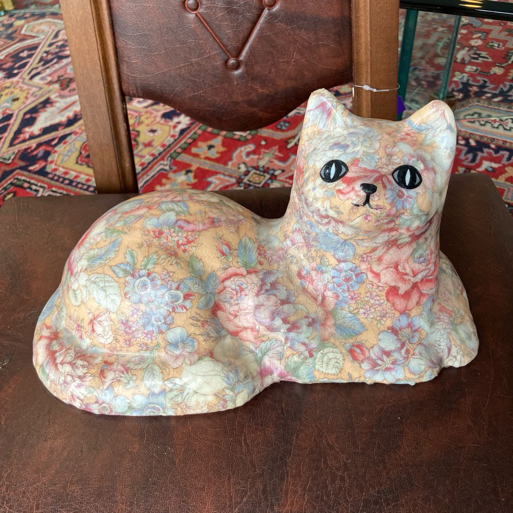 Floral-patterned cat-shaped object on a textured surface