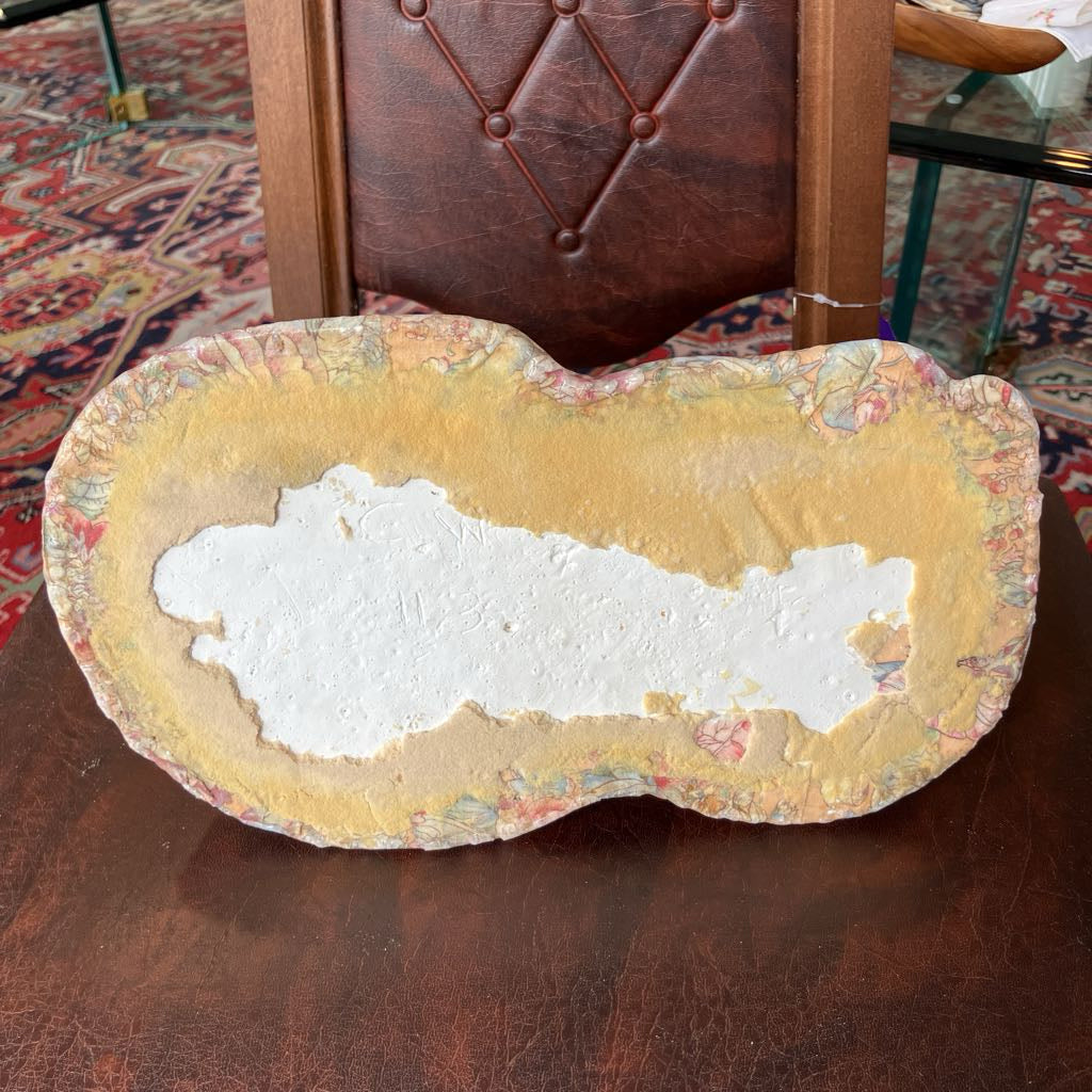 Decorative stone with a white center on a wooden surface, with a chair and patterned rug in the background.