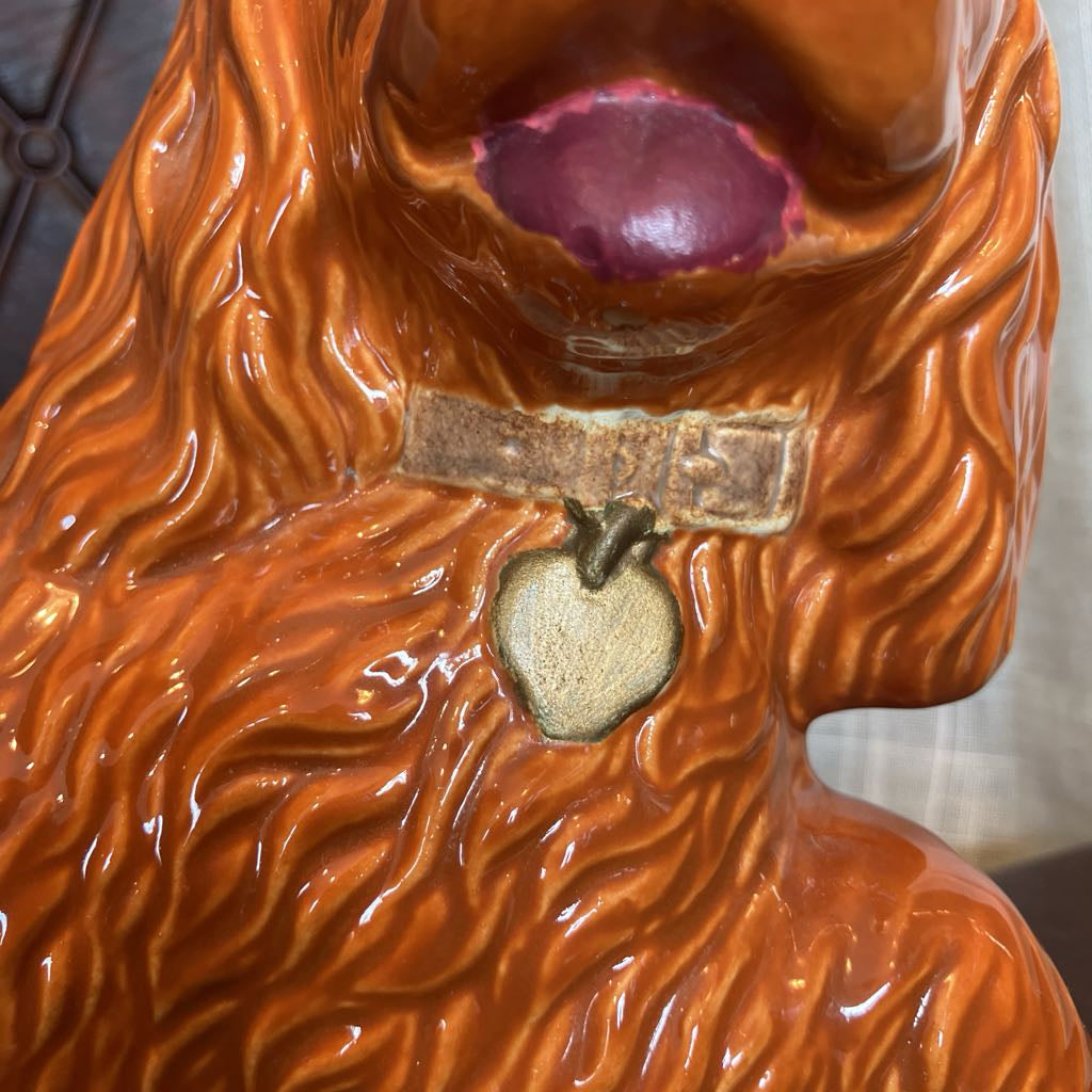 Close-up of a brown ceramic object with wavy texture and a small emblem on a white background