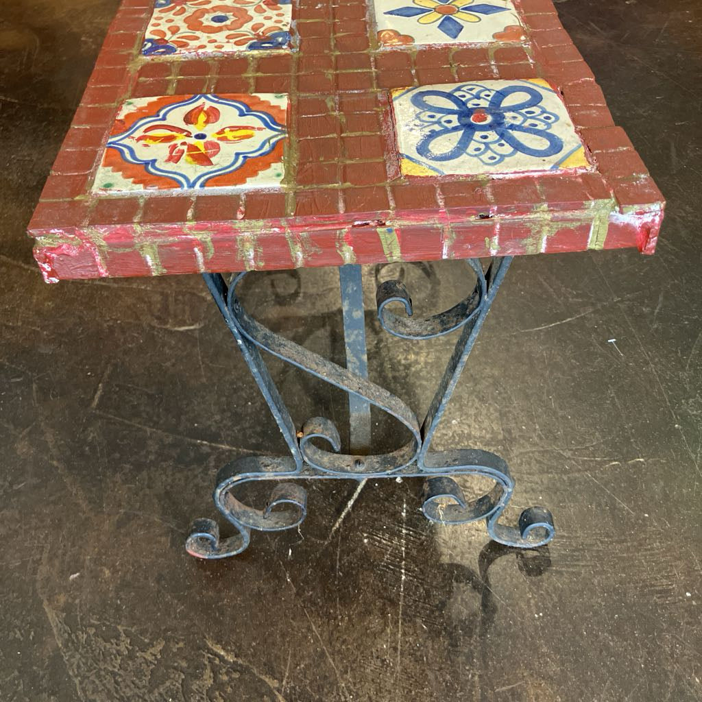 Small table with decorative tiles on a worn wooden floor