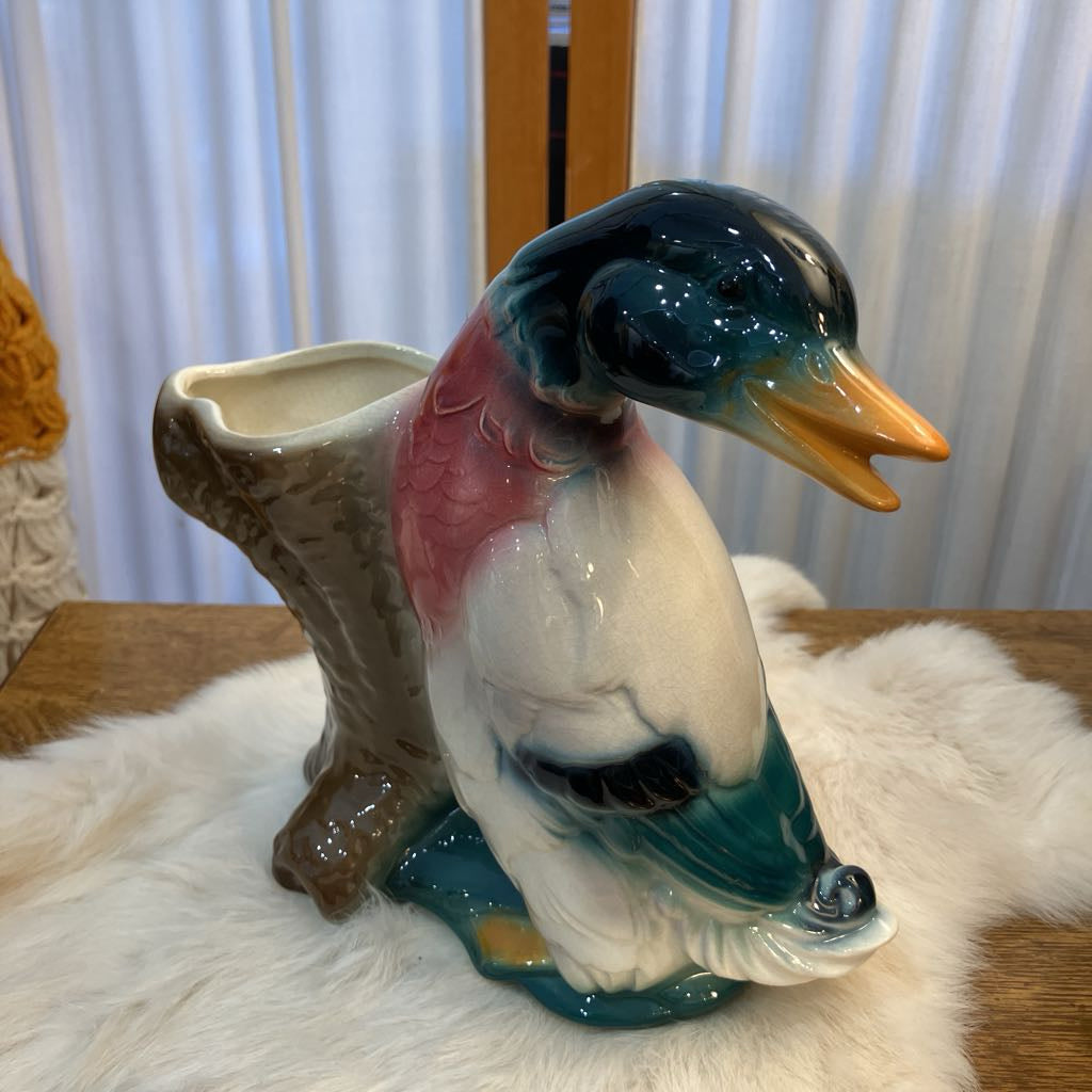 Ceramic duck figurine on a white fur surface with a blurred background