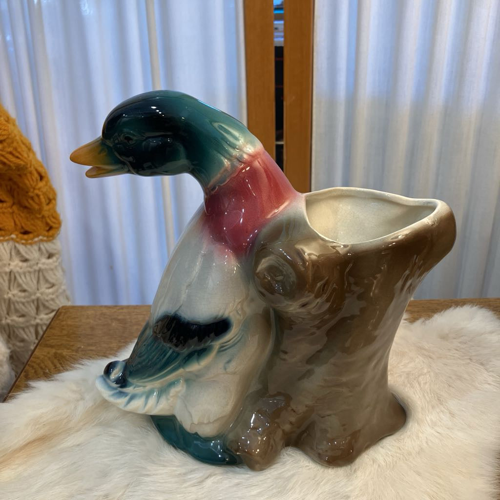 Colorful ceramic duck planter on a white surface with a blurred background