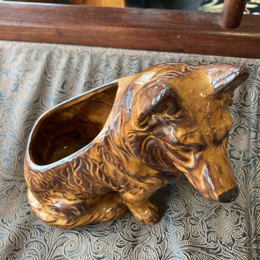 Brown ceramic dog-shaped container on a textured surface