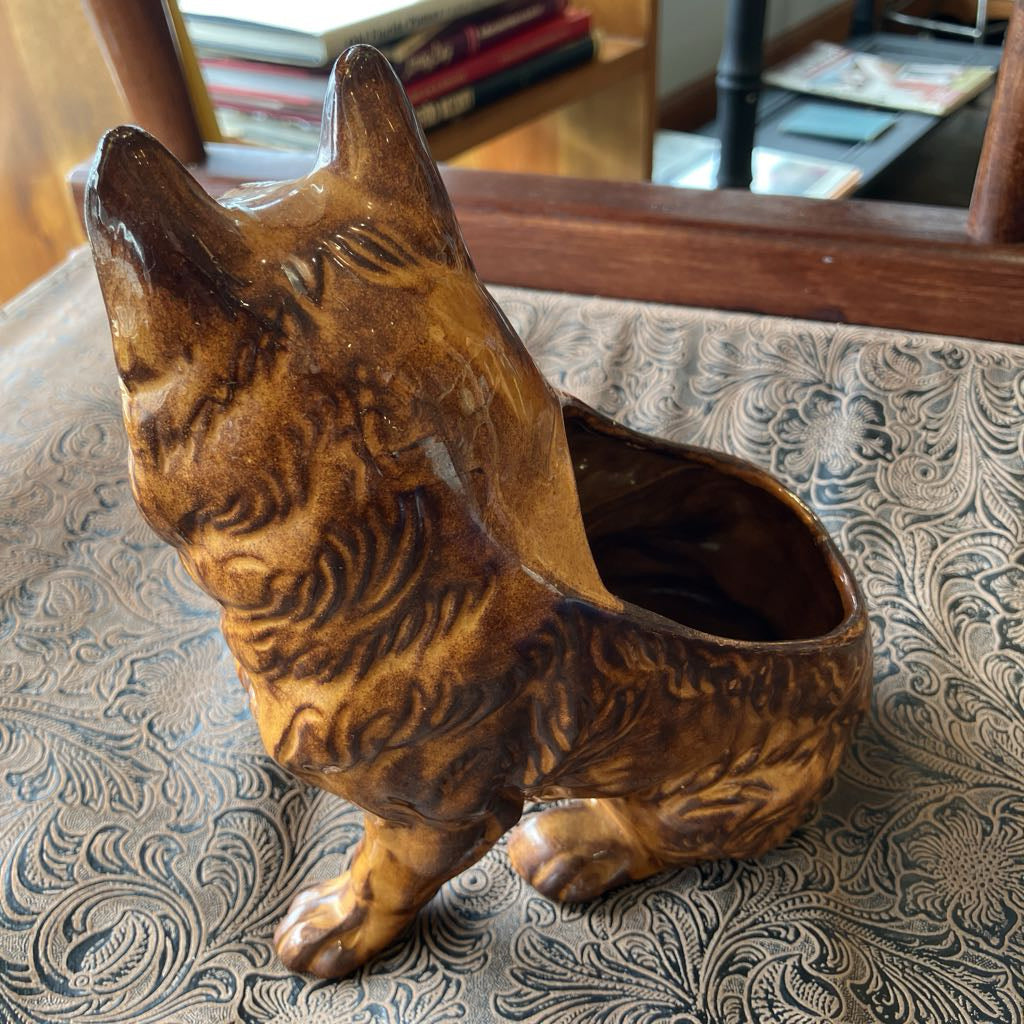 Ceramic dog-shaped planter on a textured surface with books in the background