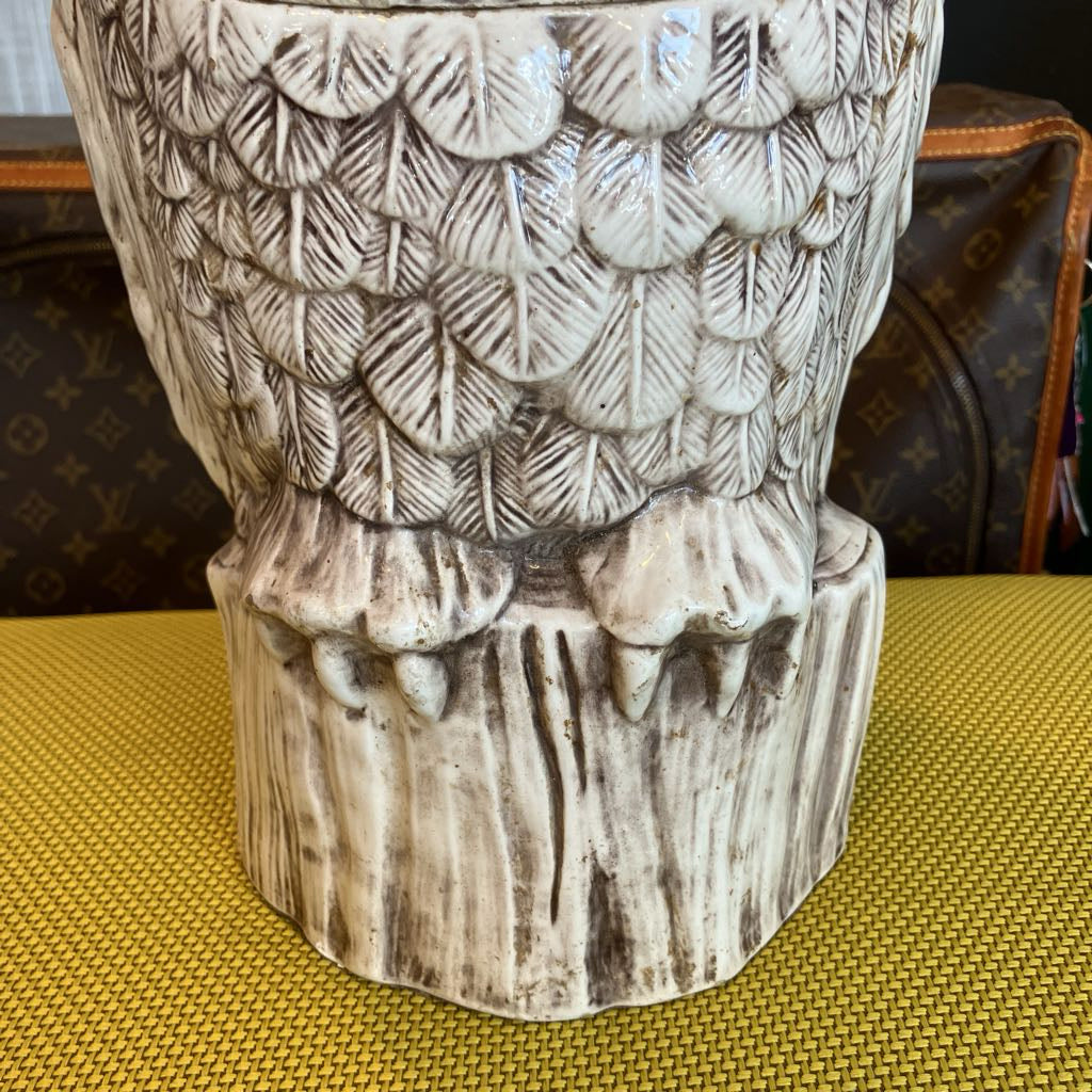 Decorative owl-shaped vase on a textured surface with a patterned background