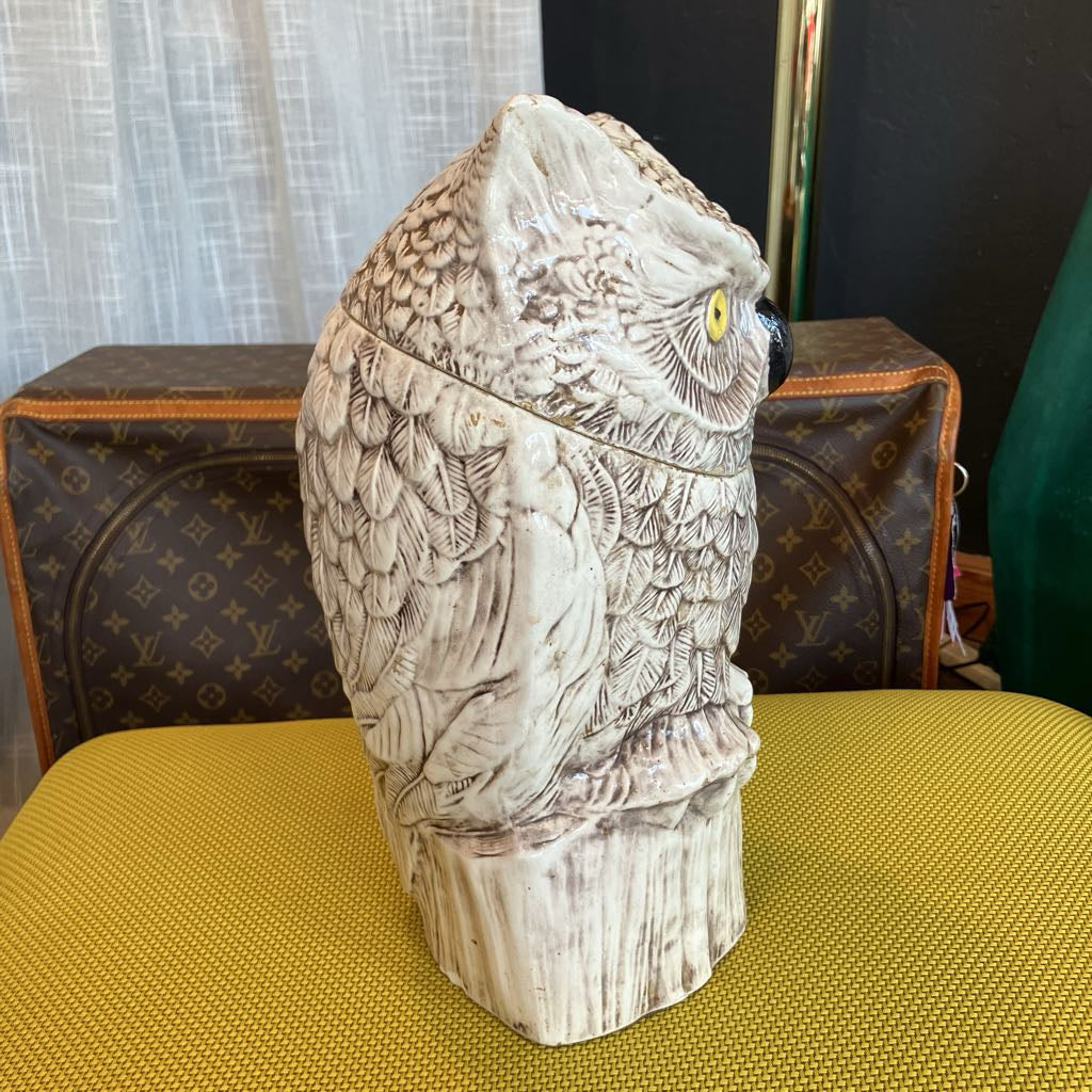 Decorative owl-shaped container on a yellow surface with a patterned background
