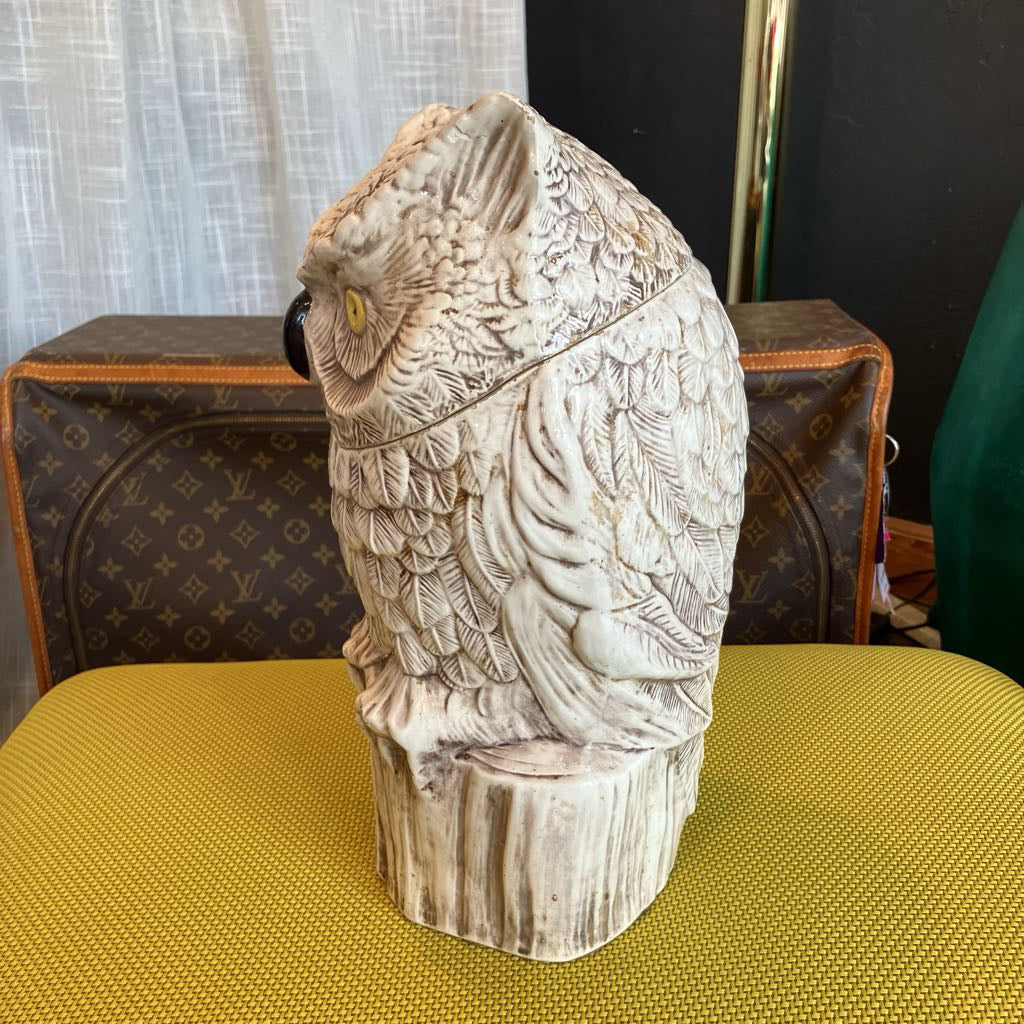 Carved owl figurine on a yellow surface with a patterned background