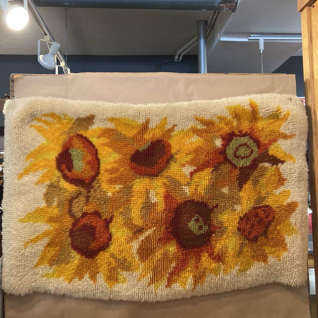 Decorative rug with sunflower pattern on a stand in an indoor setting