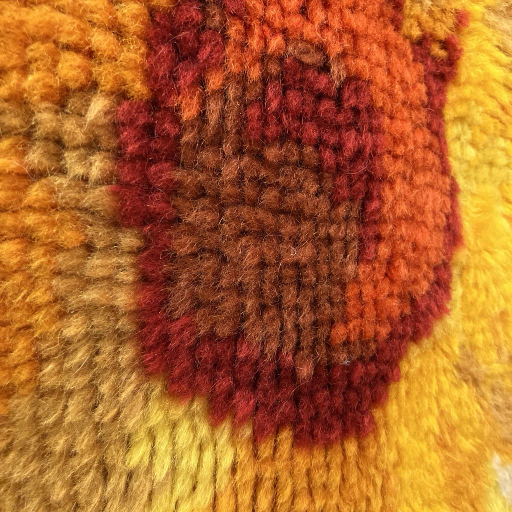 Close-up of a textured fabric with orange, red, and yellow colors.