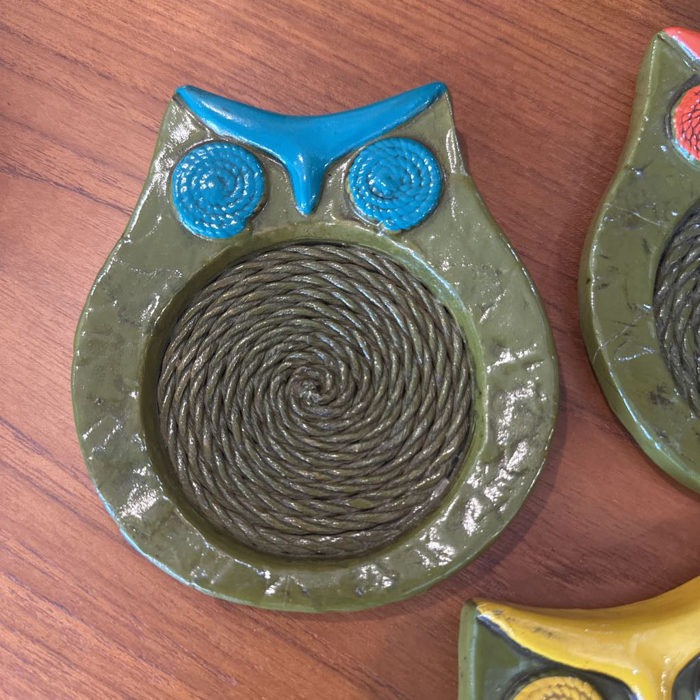 Green owl coaster toy shaped like an owl on a wooden surface