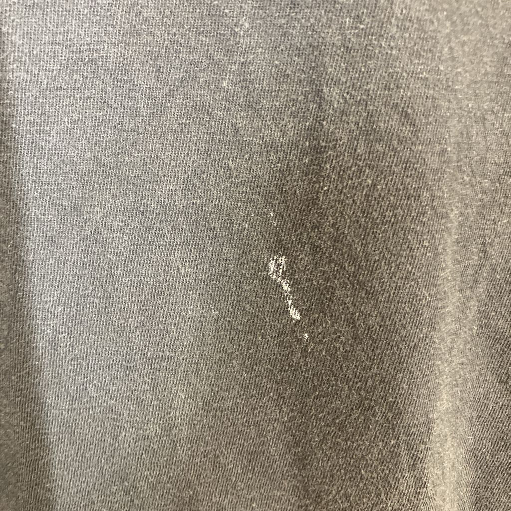 Close-up of a textured gray fabric surface with a small stain.