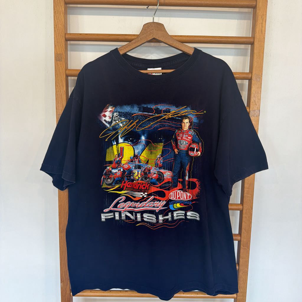 Black t-shirt with racing graphic on a wooden hanger against a white wall