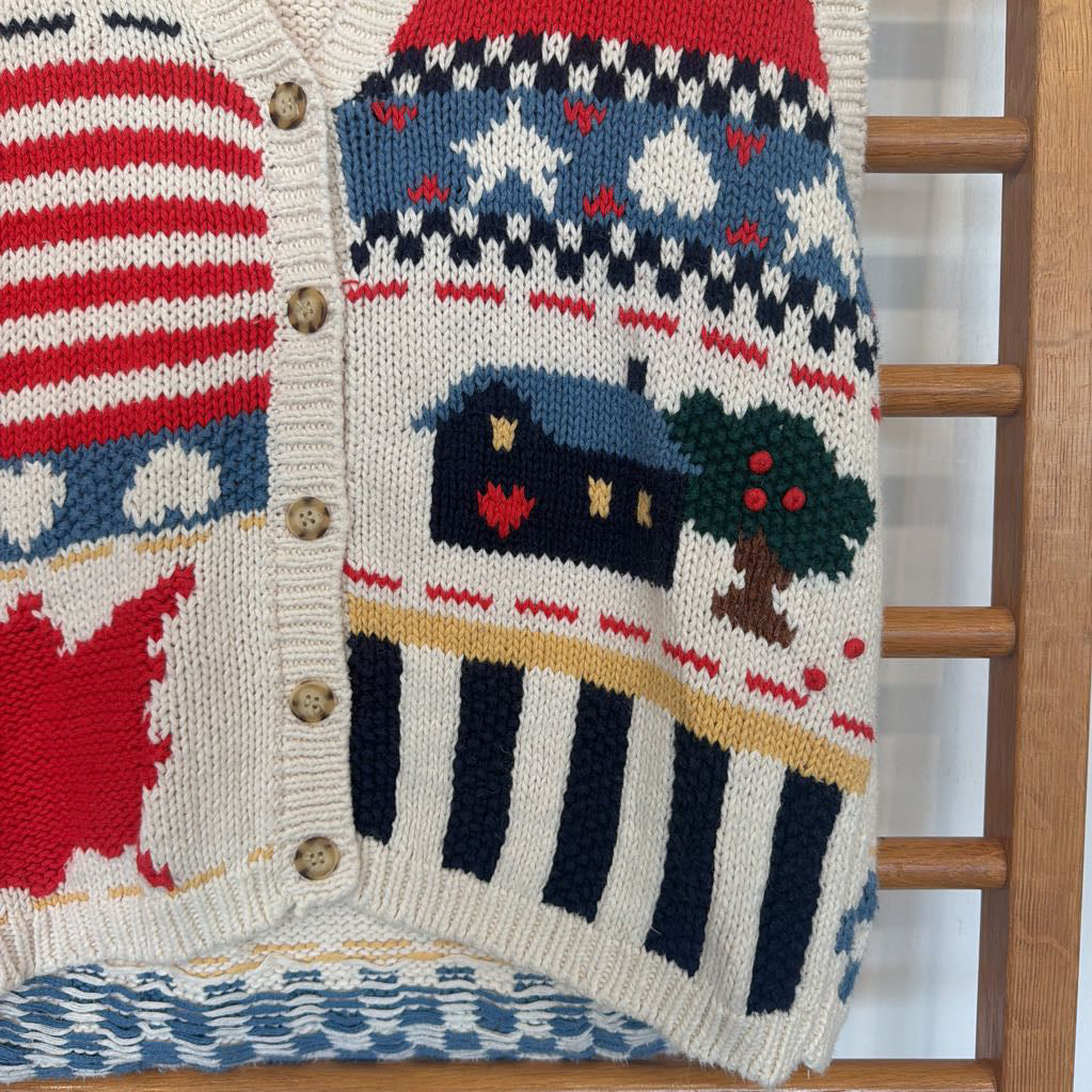 Knitted cardigan with a house and tree pattern on a wooden ladder