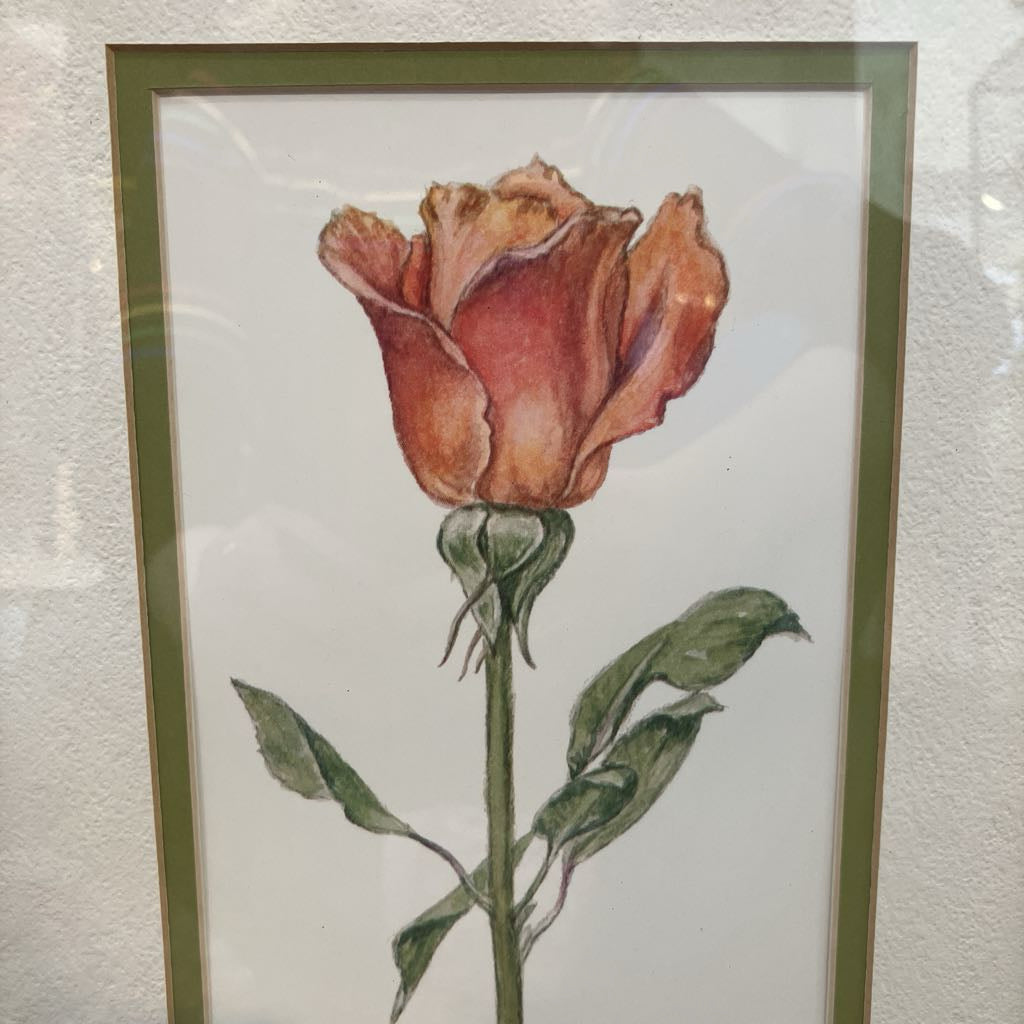 Framed artwork of a red rose on a textured wall.