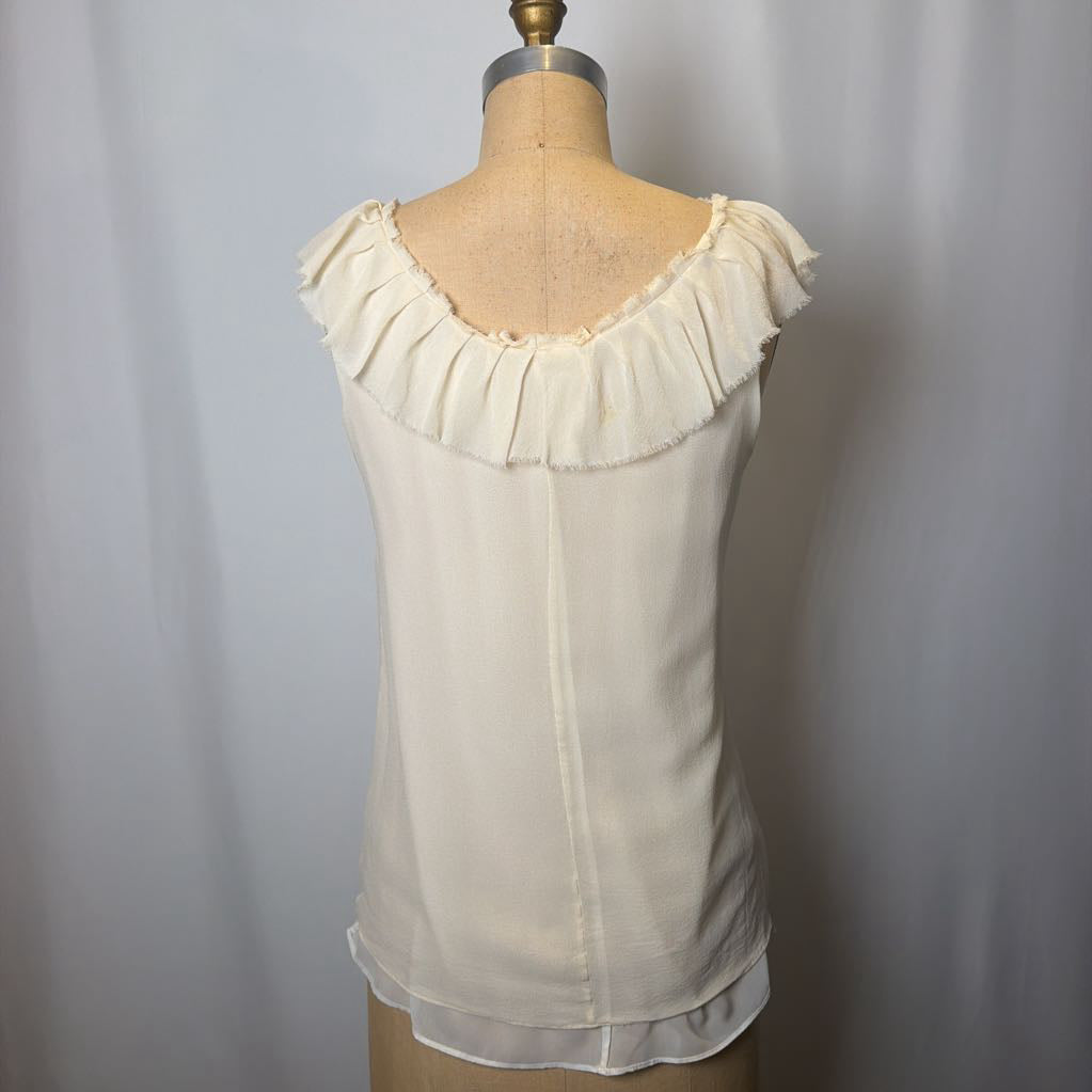 White blouse with ruffled neckline on a mannequin against a plain background