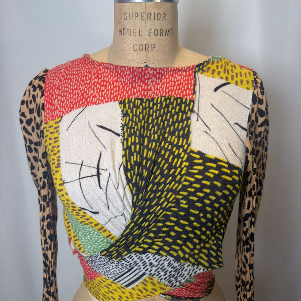 Mannequin wearing a colorful patterned top with leopard print sleeves against a plain background