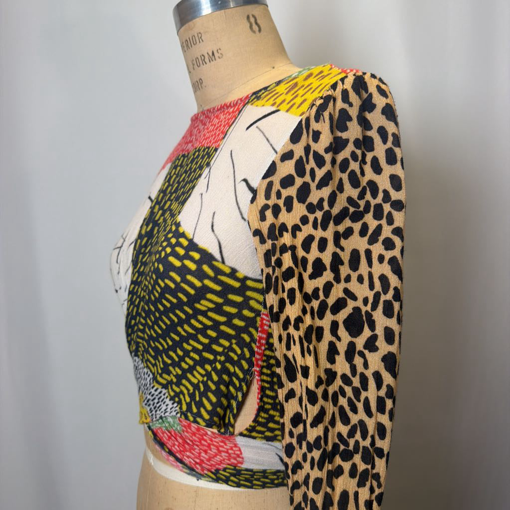 Mannequin wearing a colorful patterned garment with a leopard print sleeve.